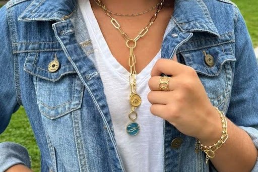 Layered gold chain necklaces with denim outfit.